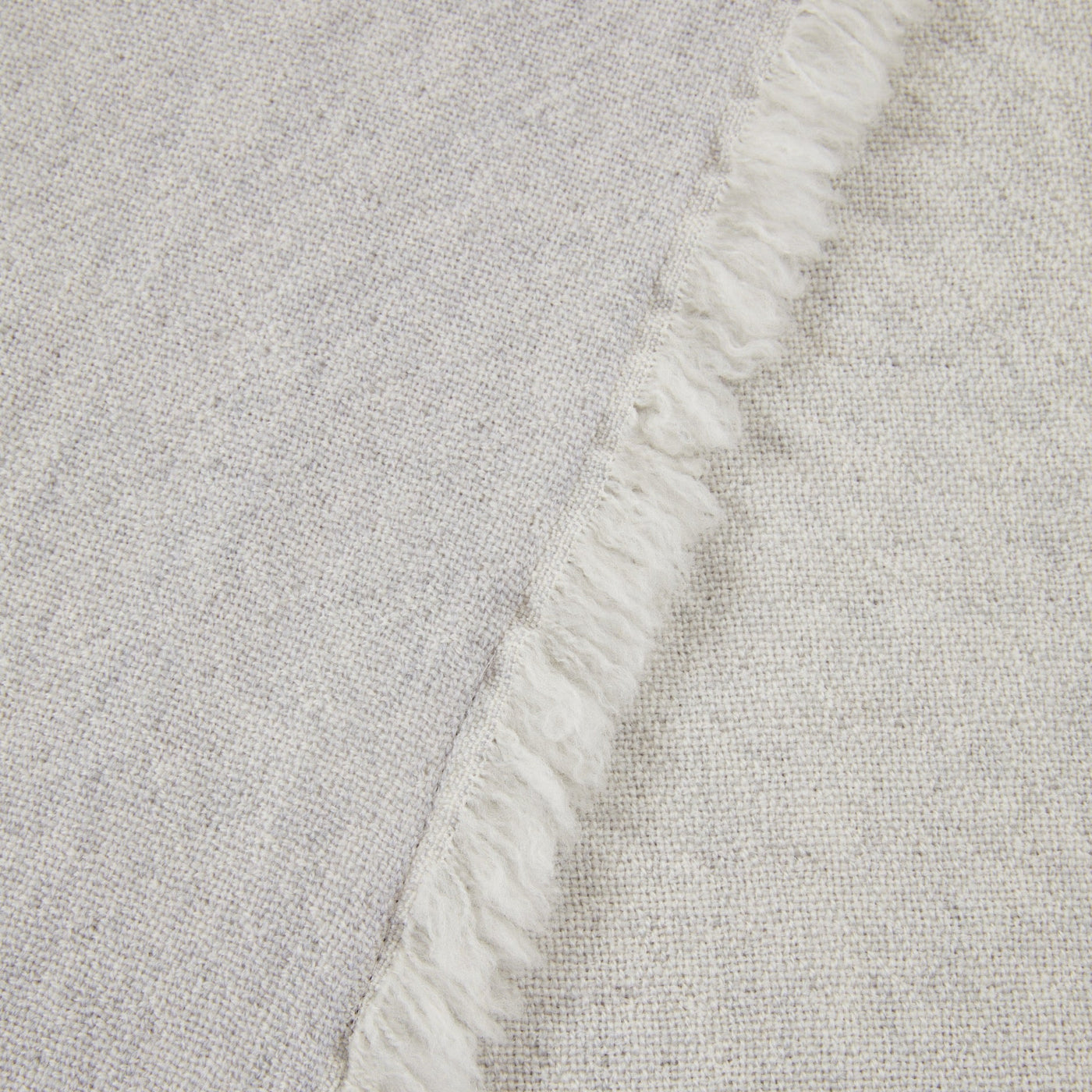 Close-up of Lanerossi Zebio throw's ivory fringe edge against a natural woven fabric.