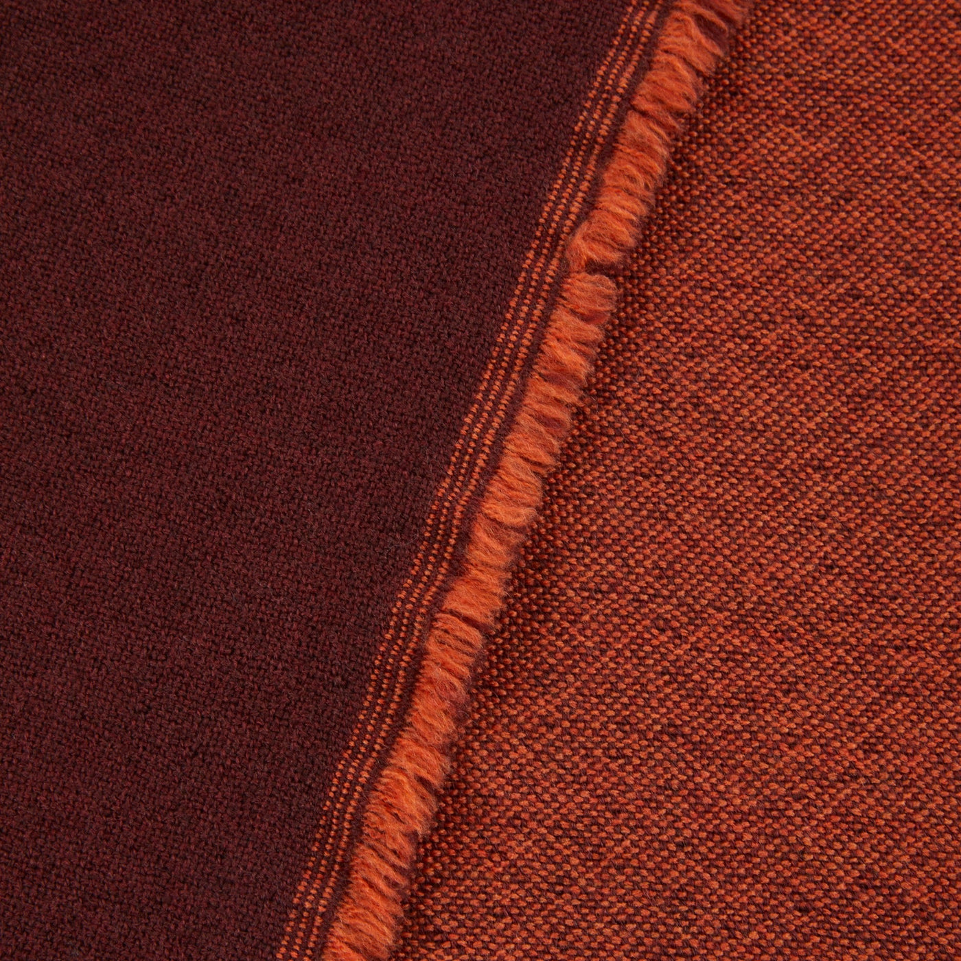 Close-up of Lanerossi Zebio blanket reversible edge, showing rust and burgundy woven sides with fringe trim.