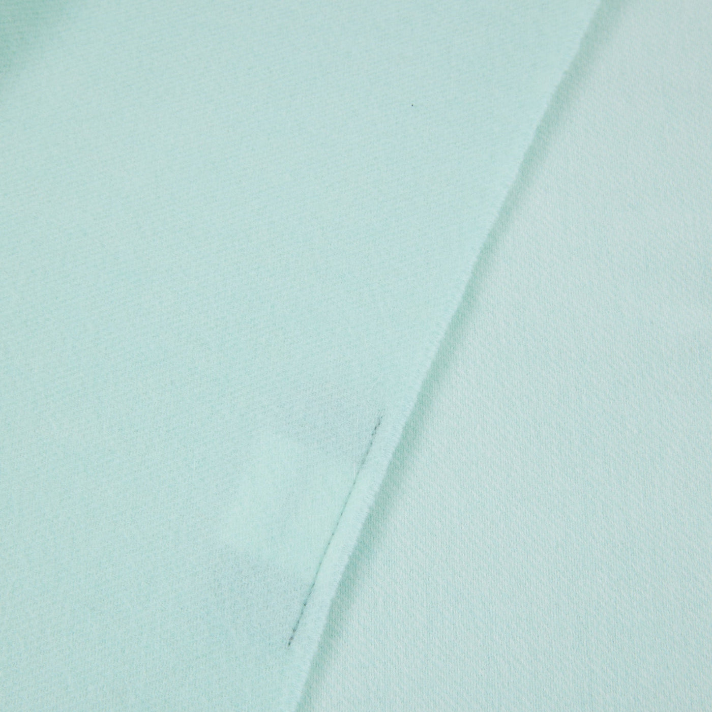 Close-up of Lanerossi Alashan throw in aqua, showing folded hem and fine weave texture.