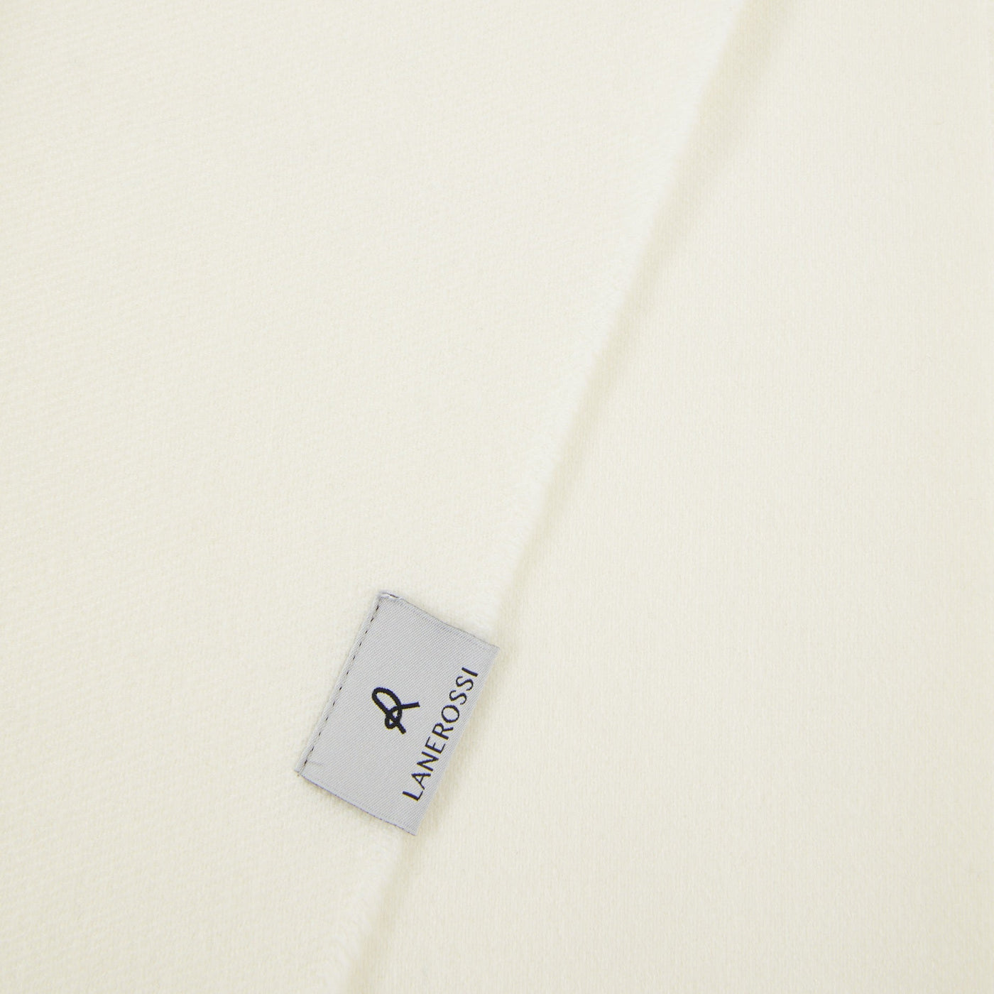 Close-up of ivory Lanerossi throw fabric with brand label at folded edge.