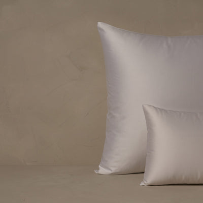 A small boudoir or travel size pillow stacked in front of a large euro size pillow. The pillow cases are made in Italy of LETTO Americano Cotton Sateen in color white, a warm and buttery American grown Supima cotton.