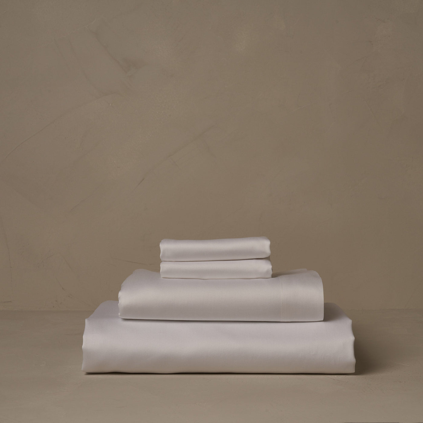 A stack of warm and buttery LETTO Americano Cotton Sateen sheets in white, made in Italy of American grown Supima Cotton. The sheet set includes a fitted sheet, a flat sheet, and a pair of pillowcases.