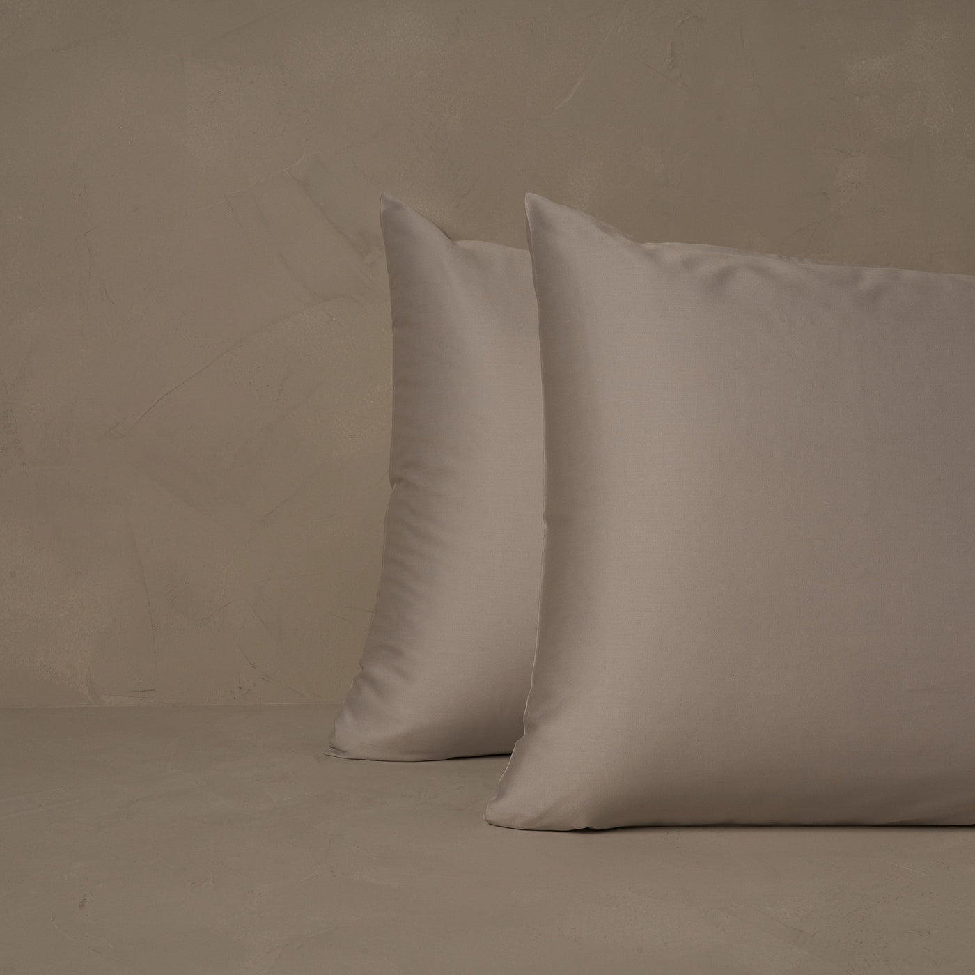 An image of two pillows stacked one in front of the other. The pillow cases are made of LETTO's warm and buttery Classic Cotton Sateen in color gray.