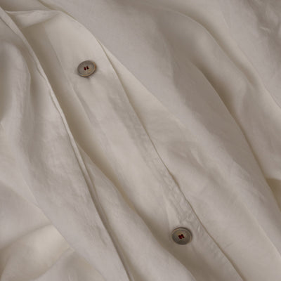 The button closure on a LETTO Classic Linen crisp and breathable duvet cover in color white.