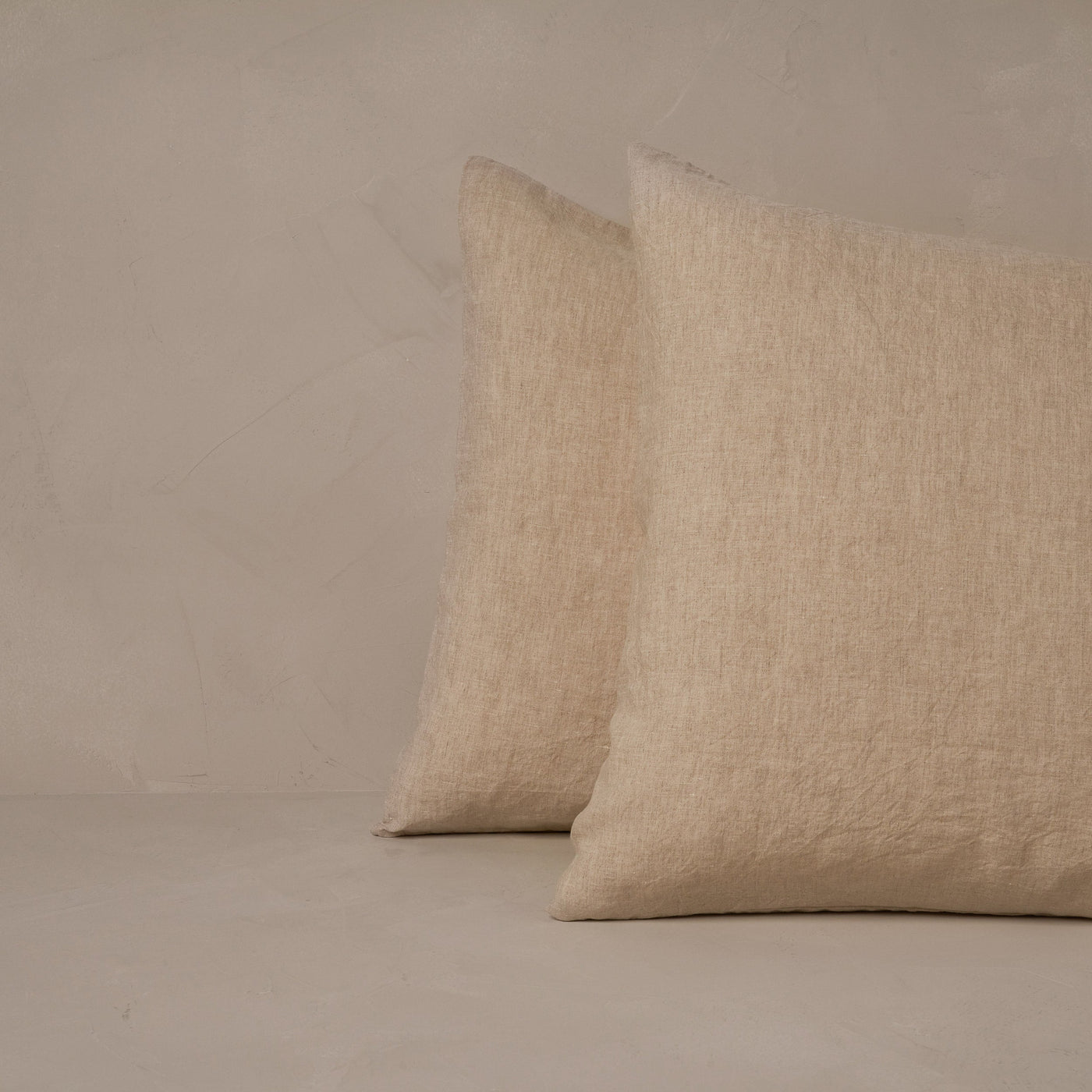 An image of two pillows stacked one in front of the other. The pillow cases are made of LETTO Classic Linen in color natural.