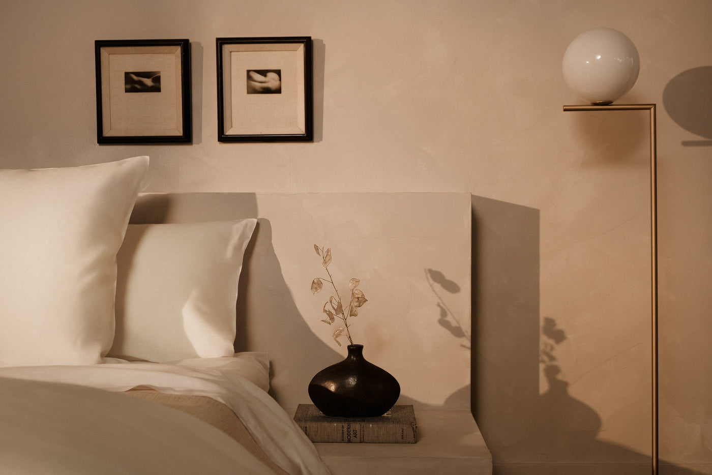 An image of LETTO Lino Primo 100% linen pillows next to a nightstand with a black vase and flowers.