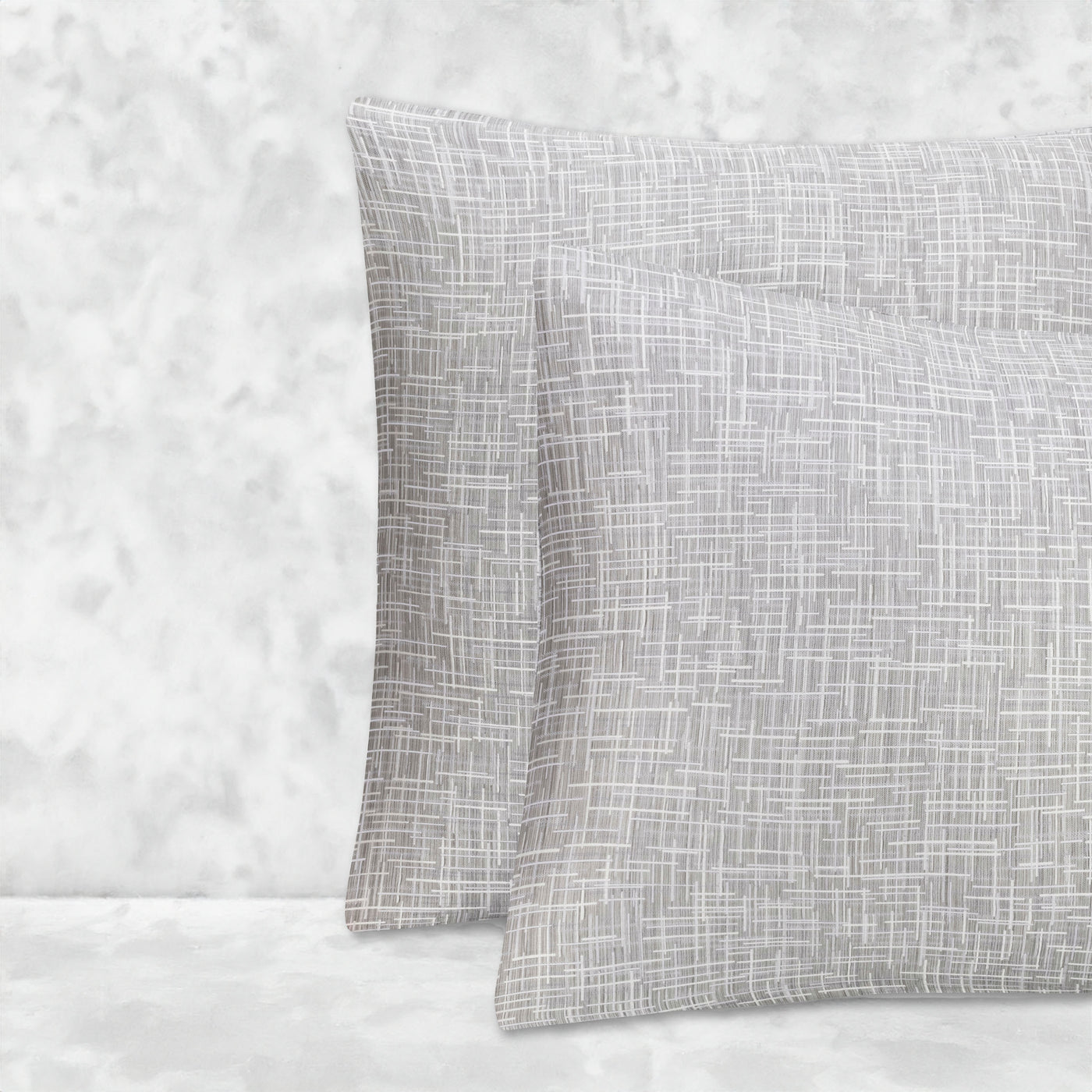 An image of two pillows stacked one in front of the other. The pillow cases are made of LETTO Mosaico Jacquard fabric in color Heather.