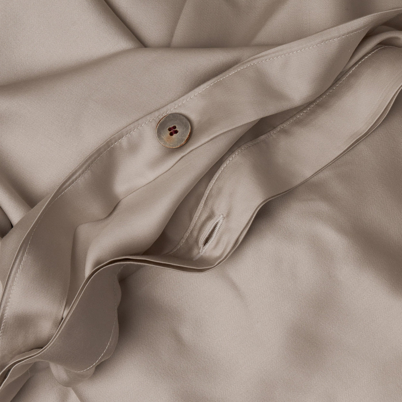 Close up image of the button closure on a LETTO Woodland Silk soft and silky duvet cover in color gray.