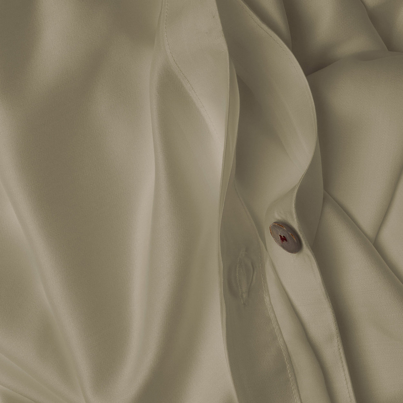 Close up image of the button closure on a LETTO Woodland Silk soft and silky duvet cover in color pistachio.