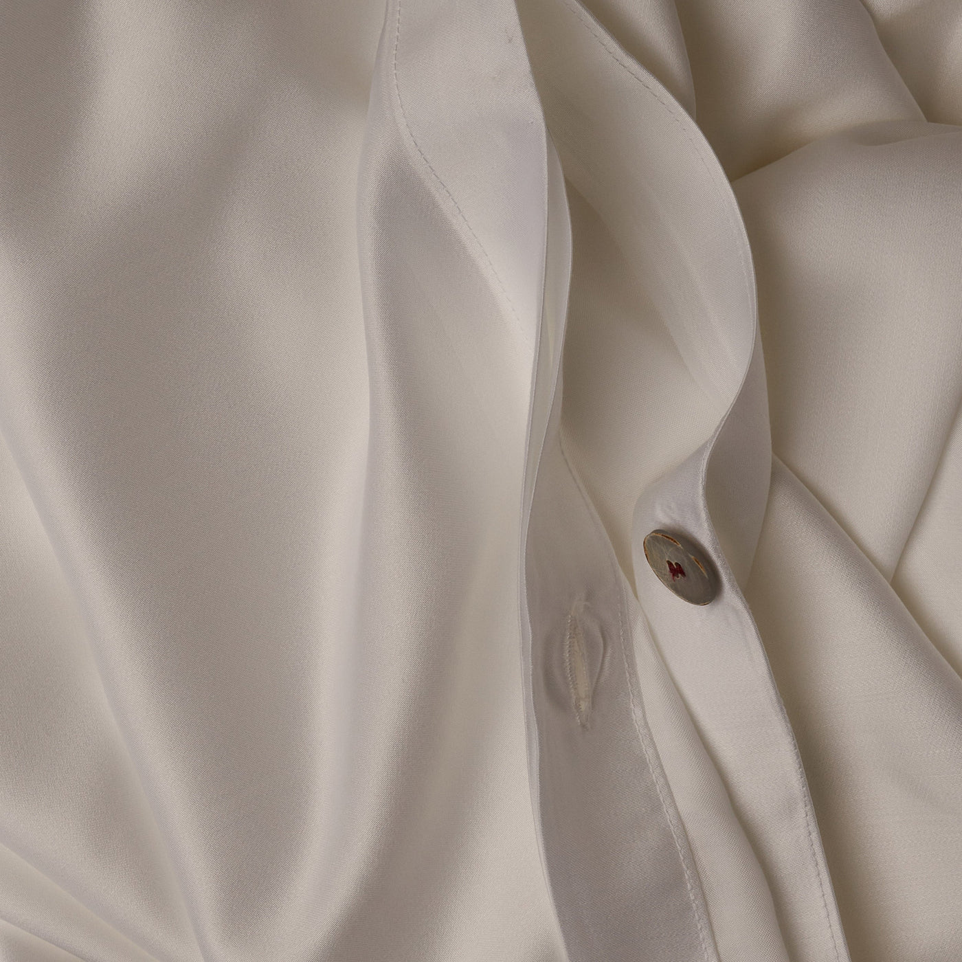 Close up image of the button closure on a LETTO Woodland Silk soft and silky duvet cover in color white.