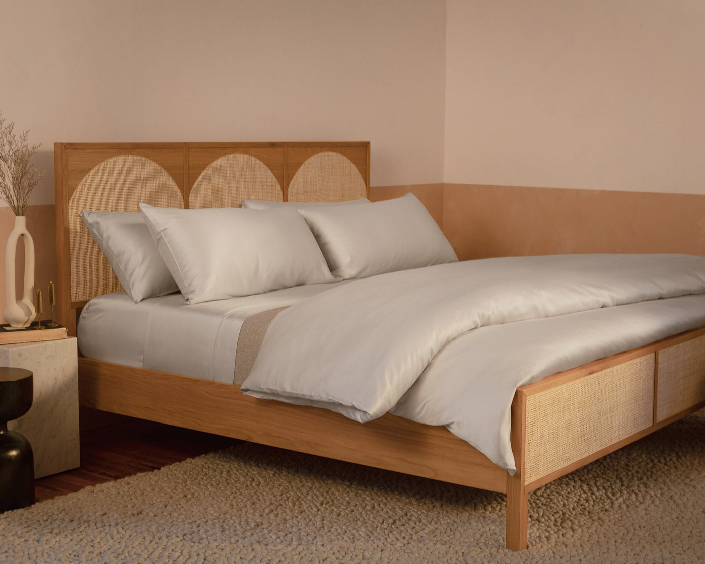 A bedroom with a contemporary wood and rattan bed made with LETTO Woodland Silk beechwood modal sheets and duvet cover in color gray.