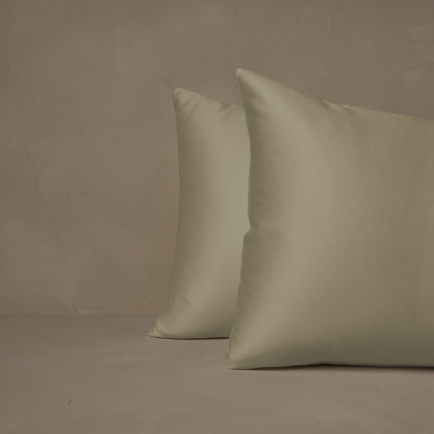 An image of two pillows stacked one in front of the other. The pillow cases are made of LETTO Woodland Silk beechwood modal in color pistacchio.