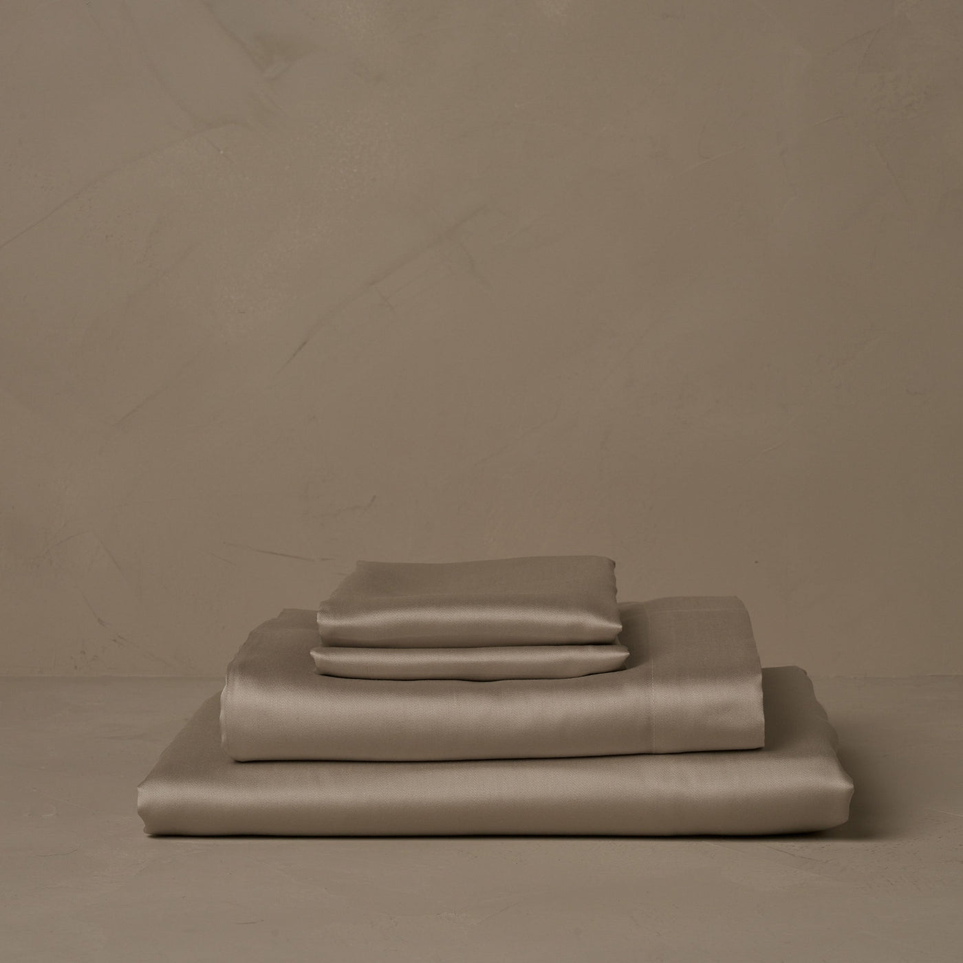 A stack of smooth and silky LETTO Woodland Silk beechwood modal sheets in candlelight, made in Italy. The sheet set includes a fitted sheet, a flat sheet, and a pair of pillowcases.