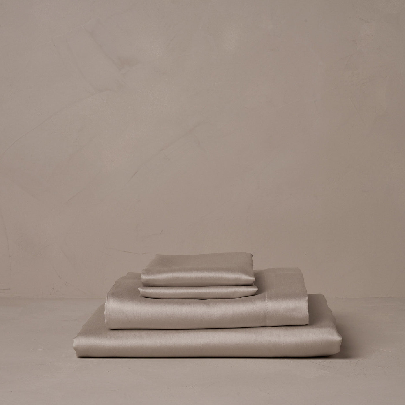 A stack of smooth and silky LETTO Woodland Silk beechwood modal sheets in gray, made in Italy. The sheet set includes a fitted sheet, a flat sheet, and a pair of pillowcases.