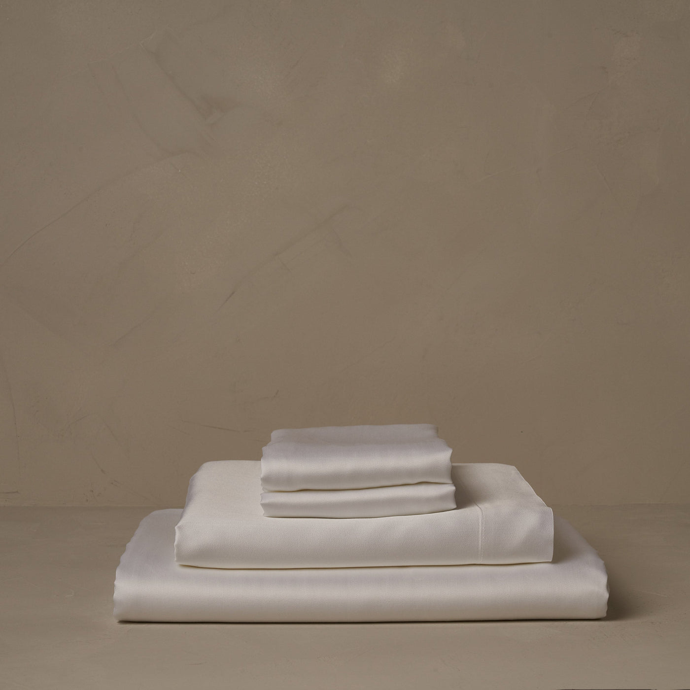 A stack of smooth and silky LETTO Woodland Silk beechwood modal sheets in white, made in Italy. The sheet set includes a fitted sheet, a flat sheet, and a pair of pillowcases.