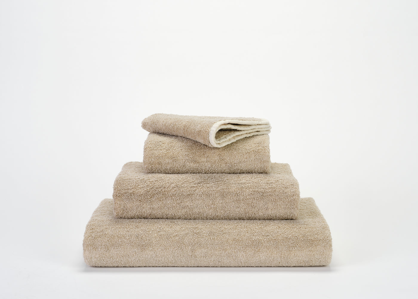 Abyss Habidecor Lino euro hand towel in sand terry cotton, stacked set of four sizes.