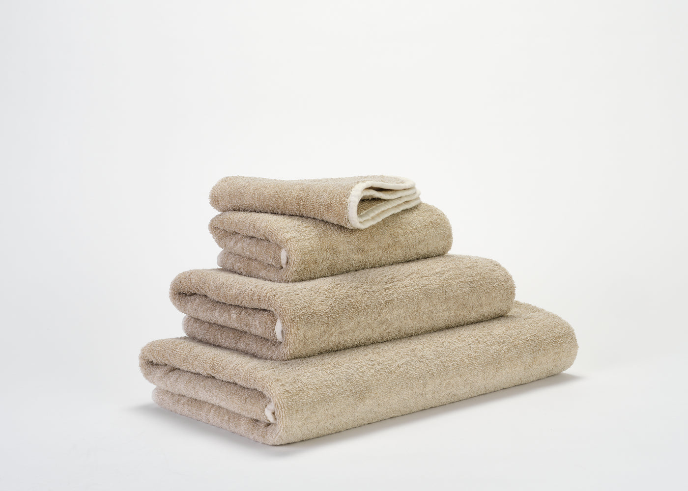 Abyss Habidecor Lino terry towel set stacked in sand, four pieces shown.
