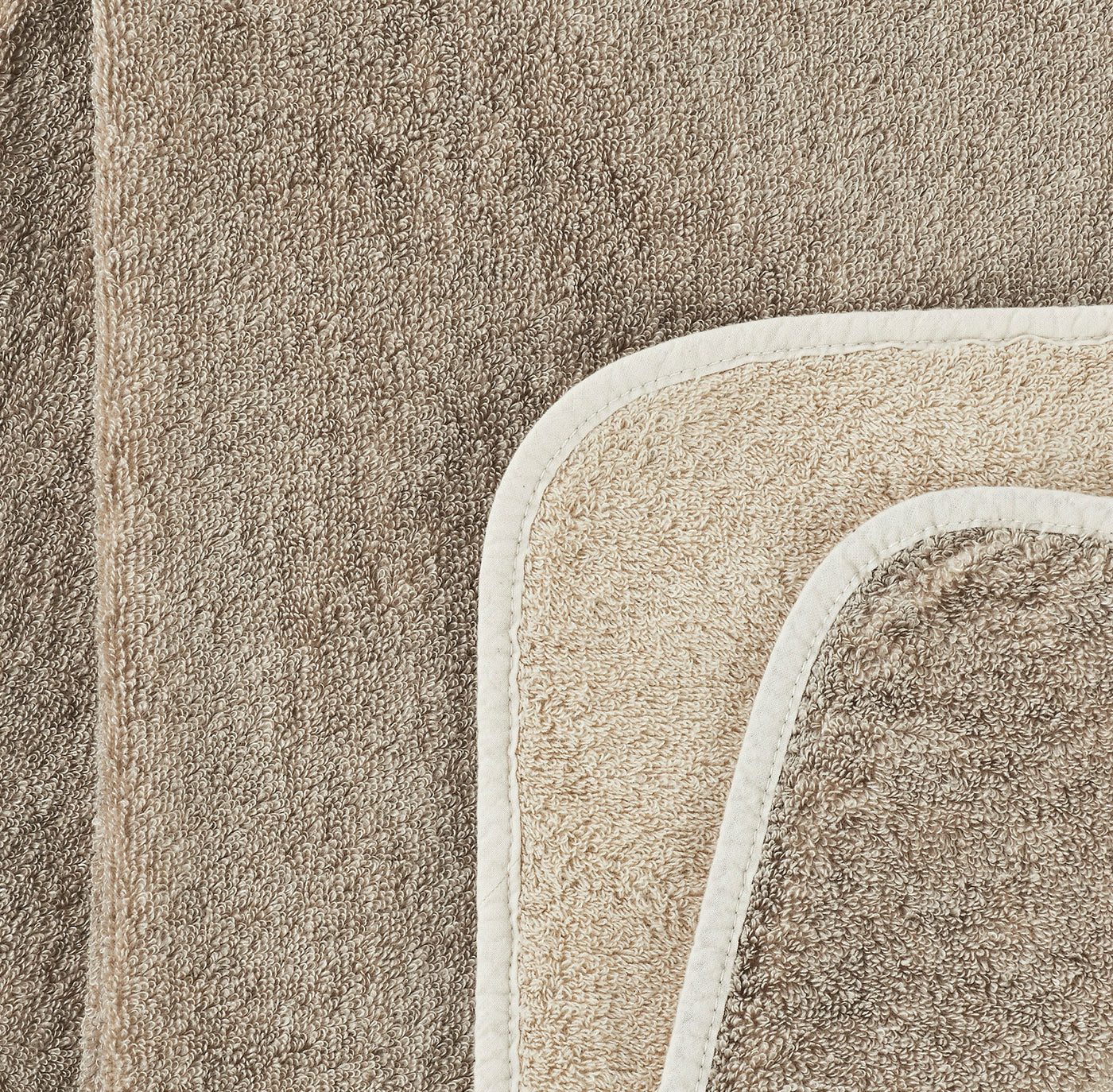 Close-up of taupe and sand terry wash mitt with ivory border detail.