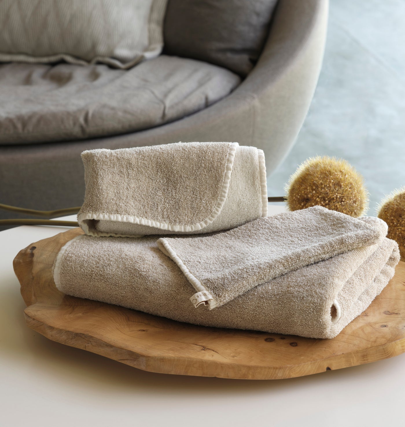 Abyss Habidecor Lino guest euro towel in sandy linen folded on a wood tray.