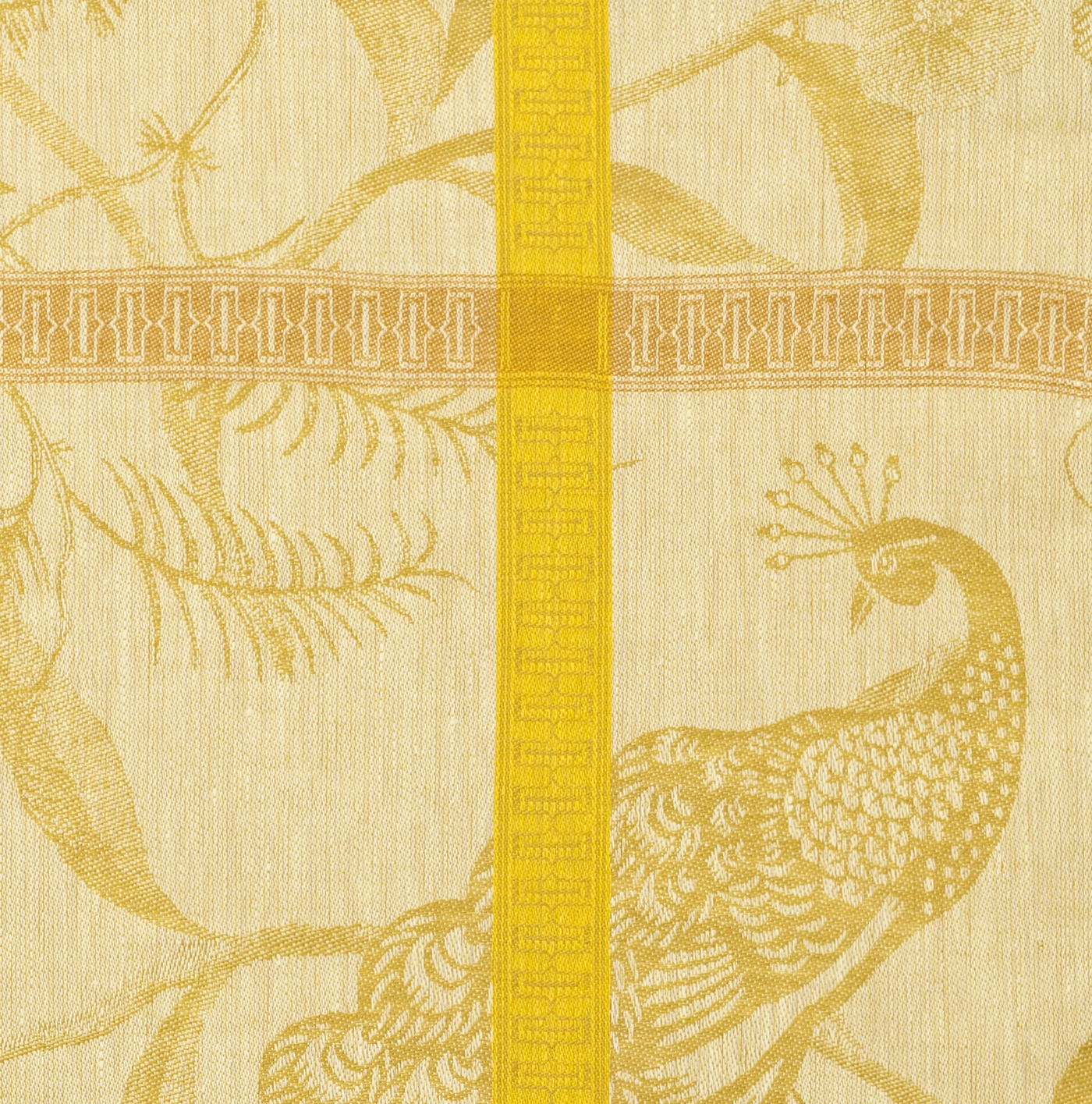 Close-up of golden peacock and floral jacquard weave with yellow woven border stripe.