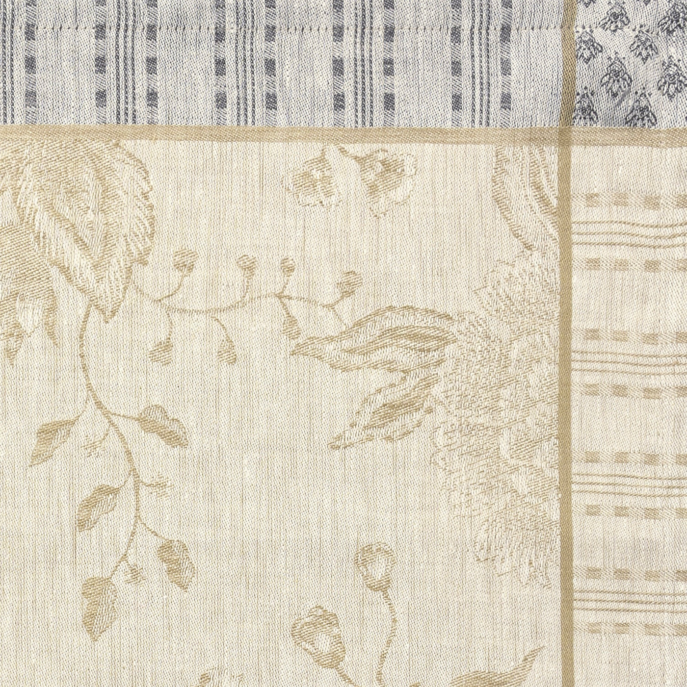 Close-up of ivory linen tablecloth with gold floral jacquard weave and striped border detail.
