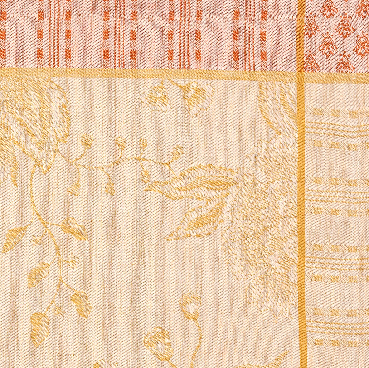 Close-up of saffron and terracotta jacquard weave with floral and geometric border detail.