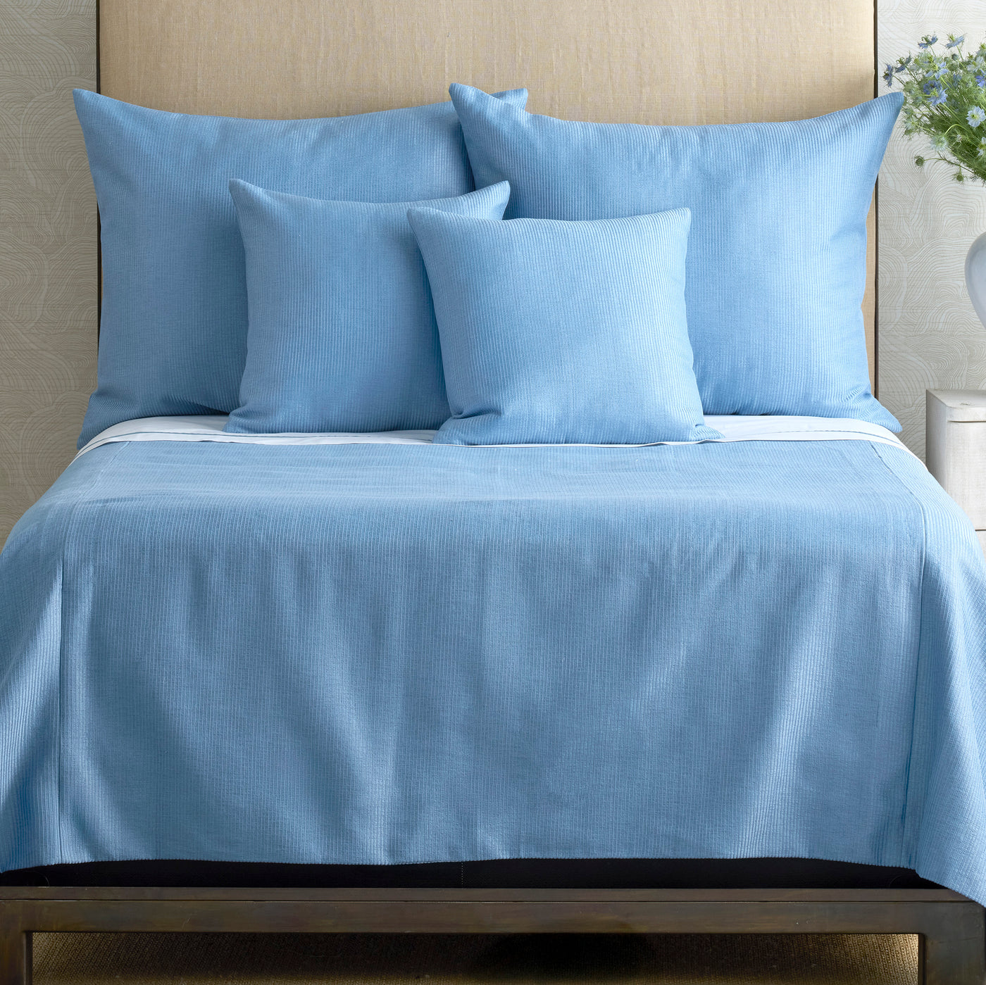 Ann Gish Lamina coverlet in sky blue with tone-on-tone stripe texture, styled on a made bed.