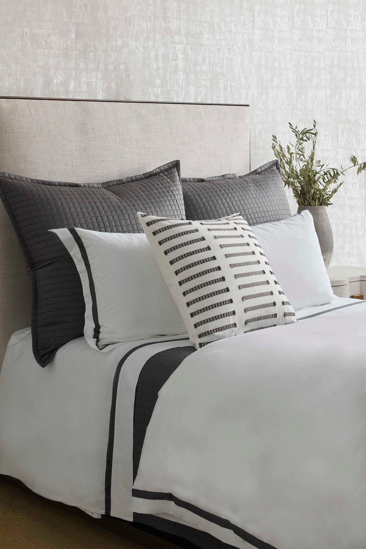 Ivory lumbar pillow with charcoal ladder stripe detail, styled on a white and grey layered bed.