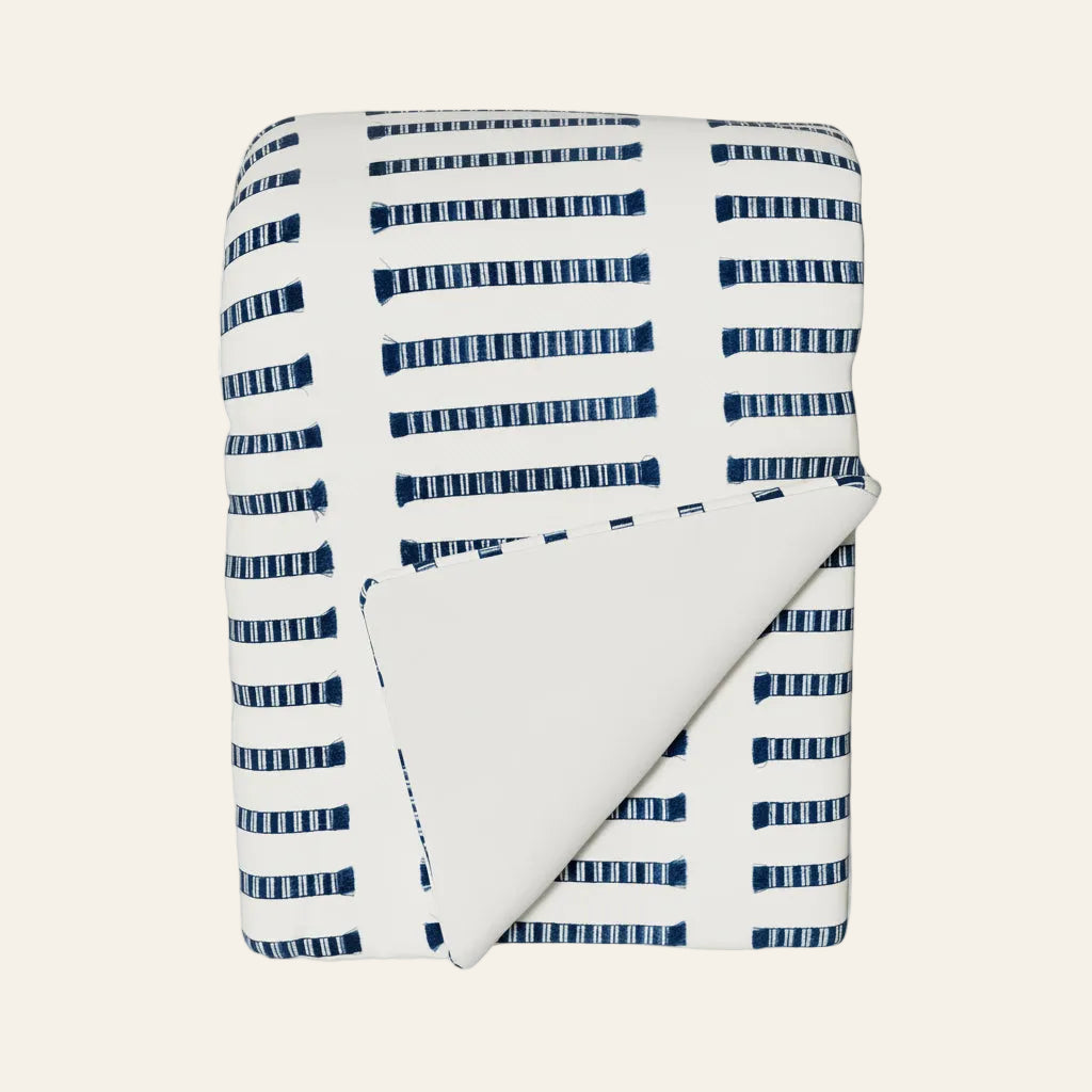Ann Gish Latera throw in ivory with navy woven stripe pattern, folded corner revealing solid reverse.