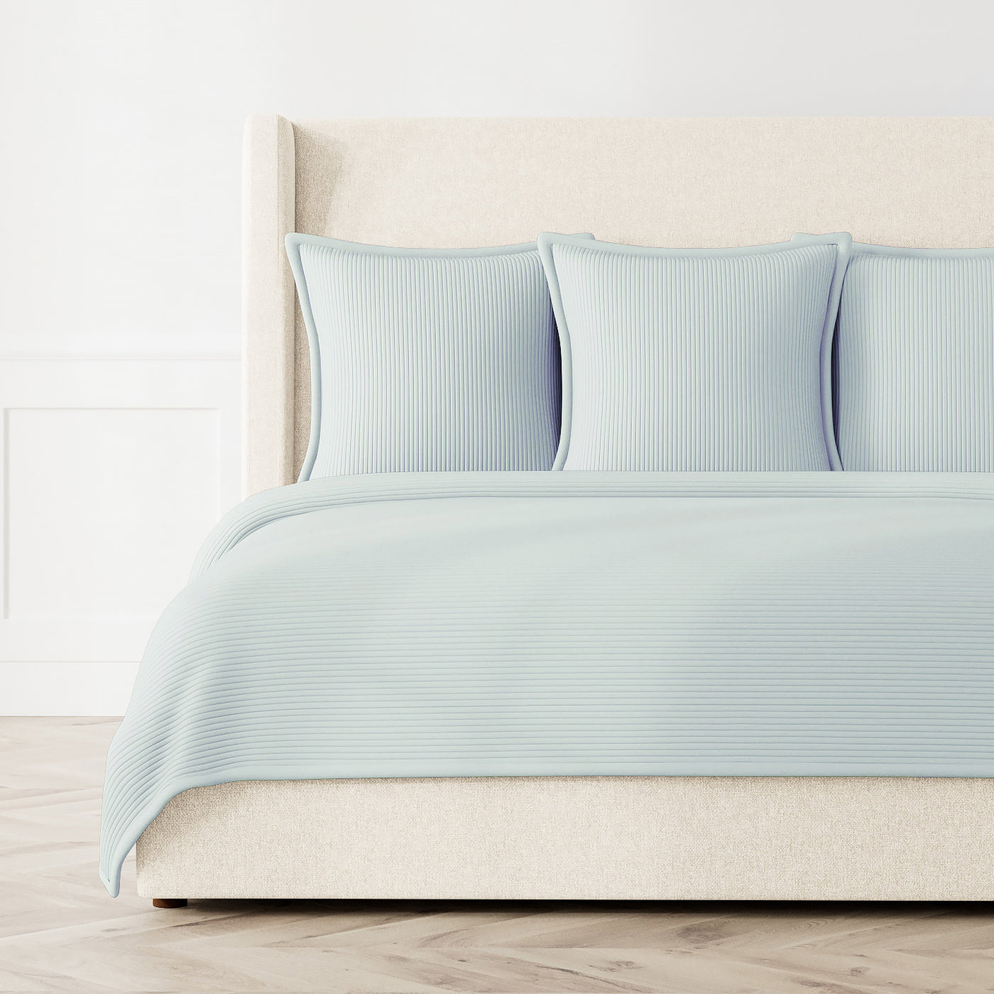 Pale blue coverlet with tonal stripe texture, styled on a bed with matching shams.