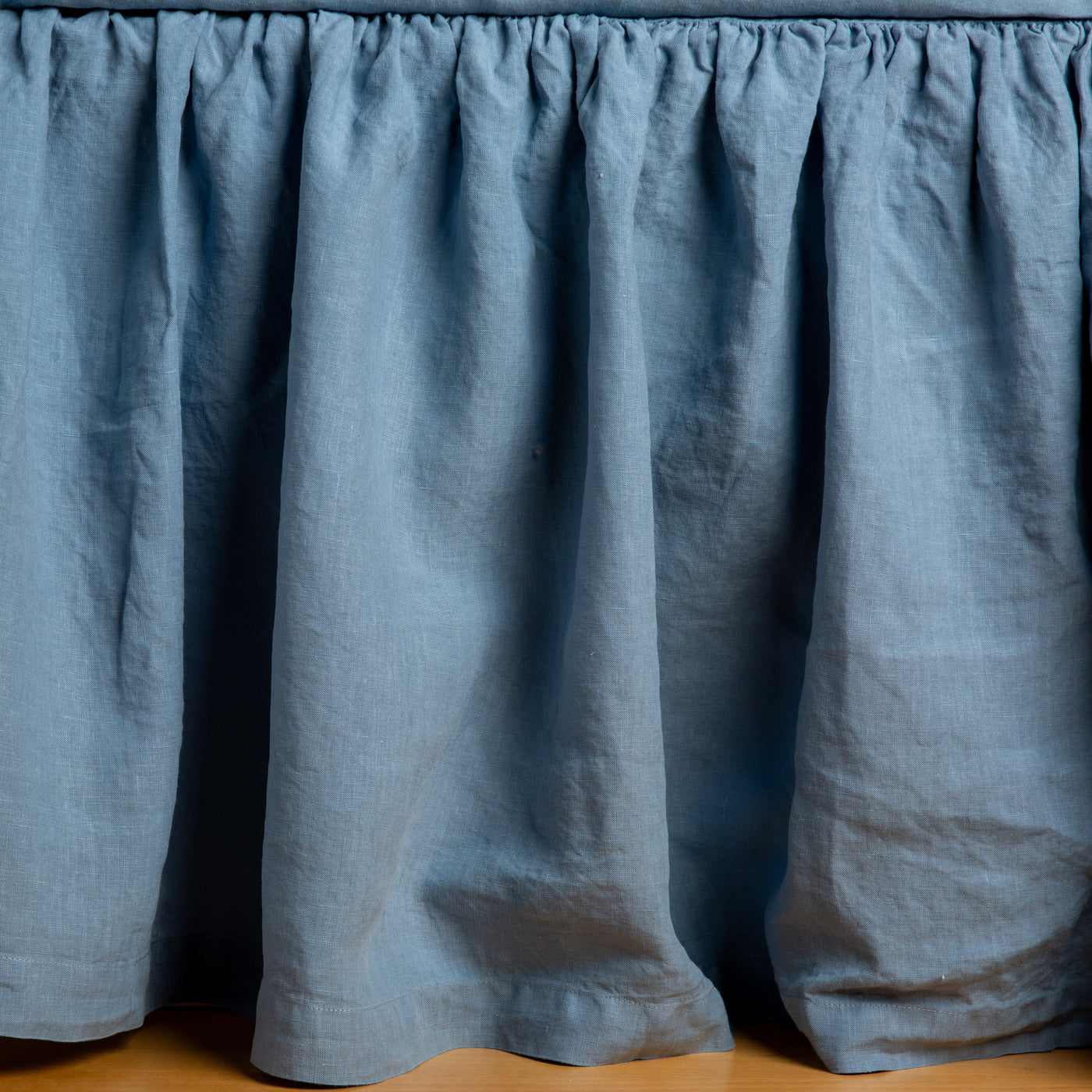 Gathered Bella Notte linen bed skirt in Tahoe Blue, showing full drape and gathered header detail.