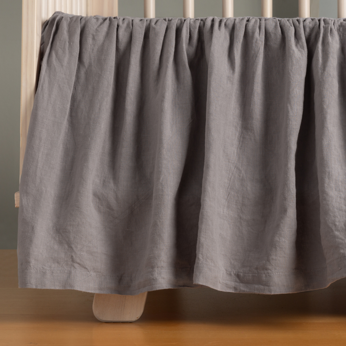 Gathered French Lavender linen crib skirt draped along crib base, floor-length view.
