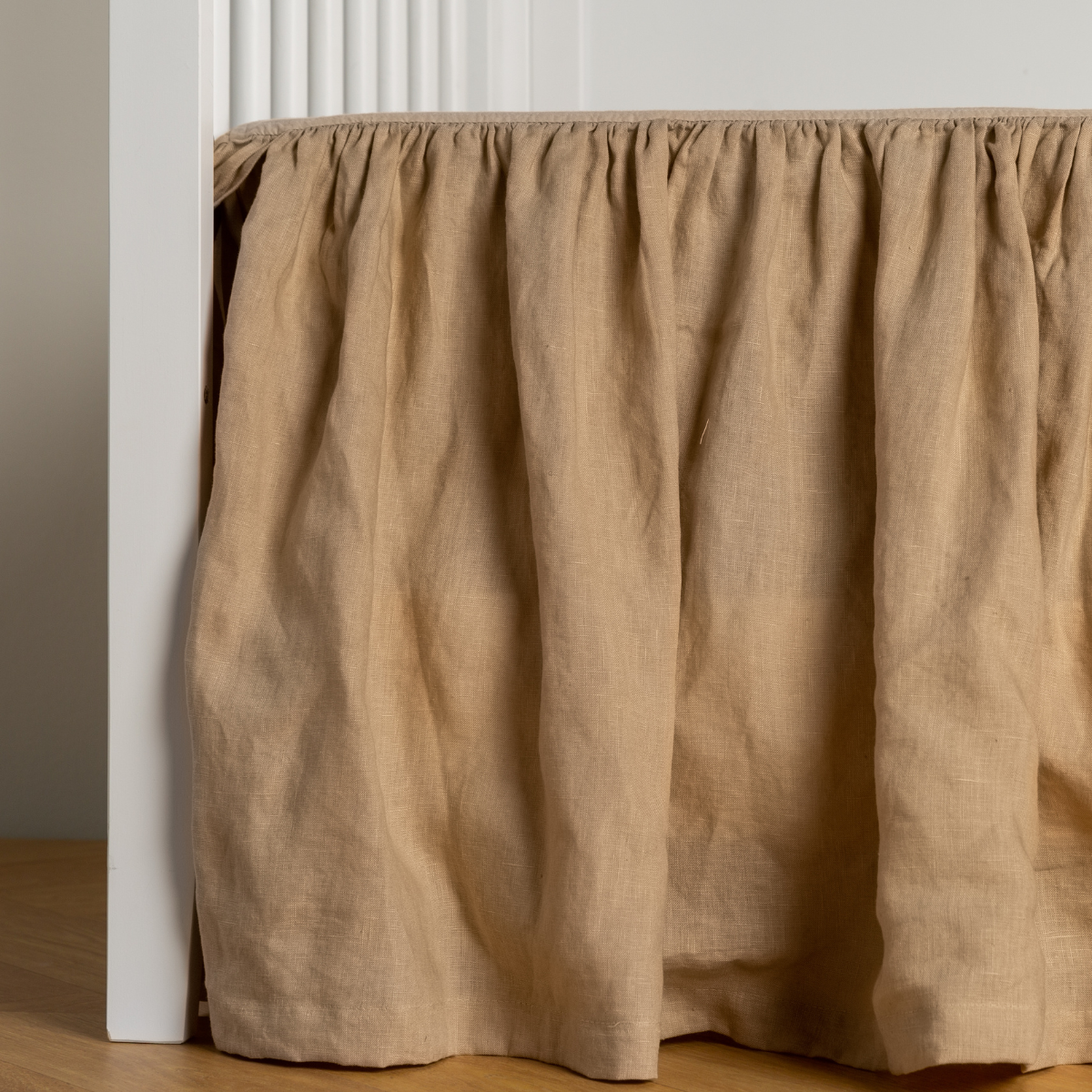 Gathered Honeycomb linen crib skirt draping to the floor, close side view.