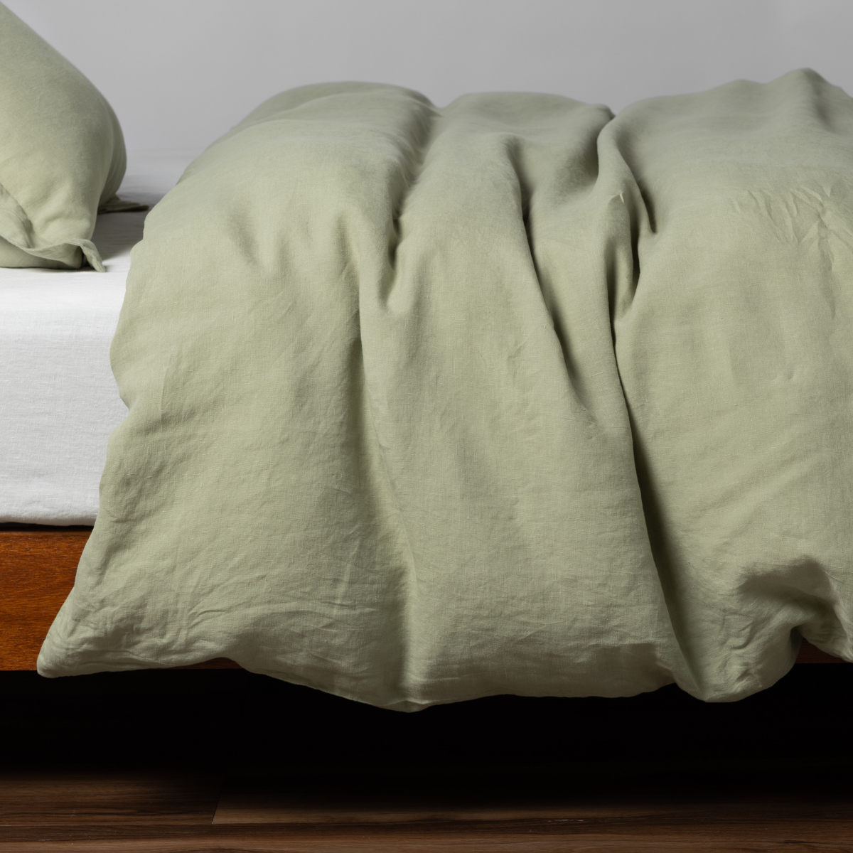 Relaxed Desert Sage linen duvet cover draped over bed, showing natural texture and soft folds.