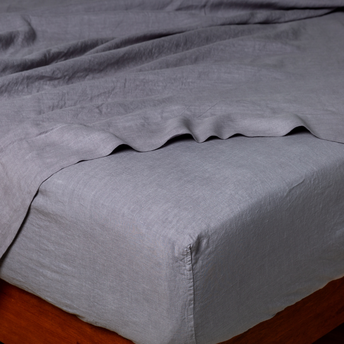 Bella Notte French Lavender linen fitted sheet on bed, showing elasticized corner and relaxed drape.