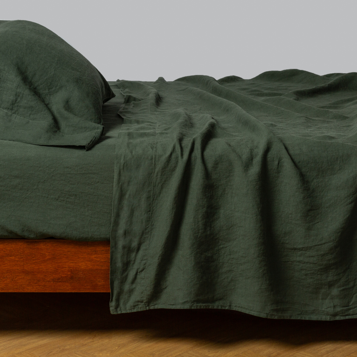 Juniper linen flat sheet draped loosely over a wood-frame bed with matching pillowcases.