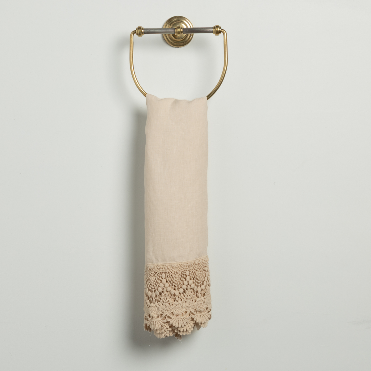Bella Notte Mattine guest towel in Natural, showing crochet lace hem detail on brass ring holder.