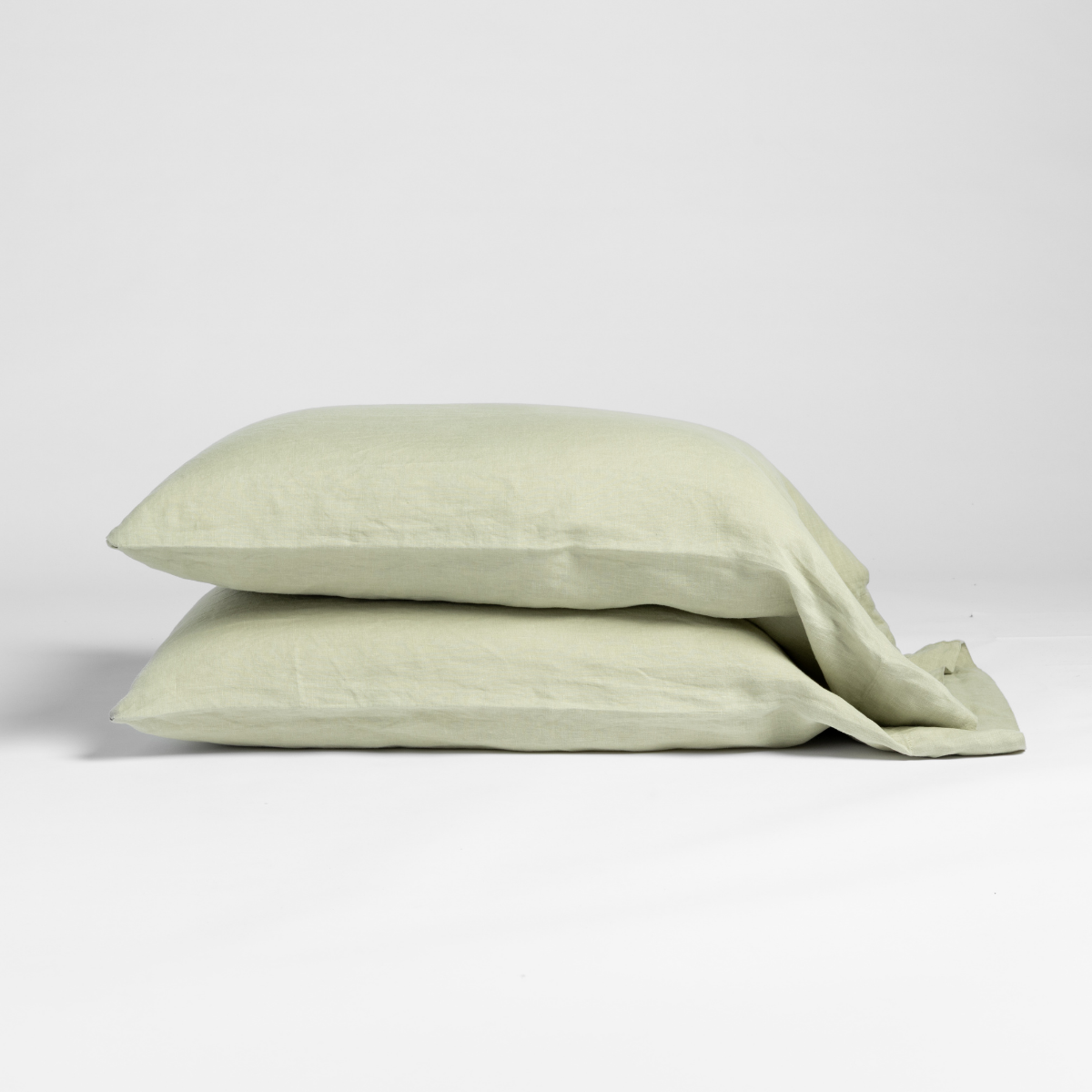 Two Desert Sage Bella Notte linen pillowcases stacked, showing relaxed texture and envelope closure.
