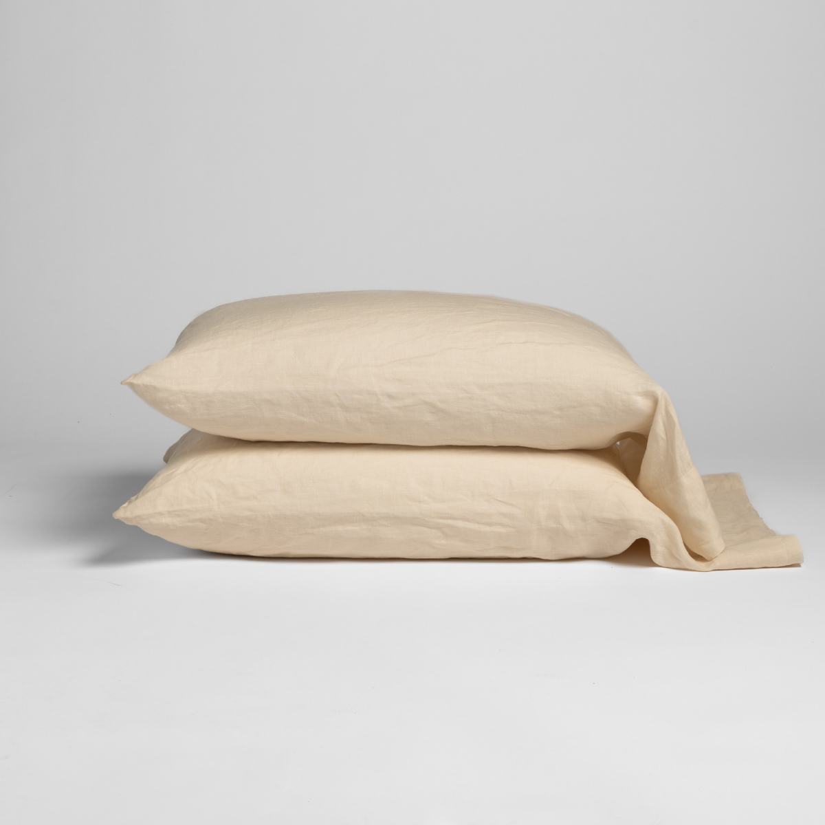 Bella Notte Linen pillowcase pair stacked in Natural, fabric tail draped to side.