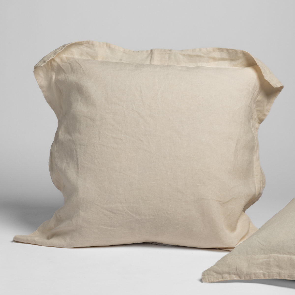 Natural linen sham with flange trim, shown upright with a second sham angled in foreground.