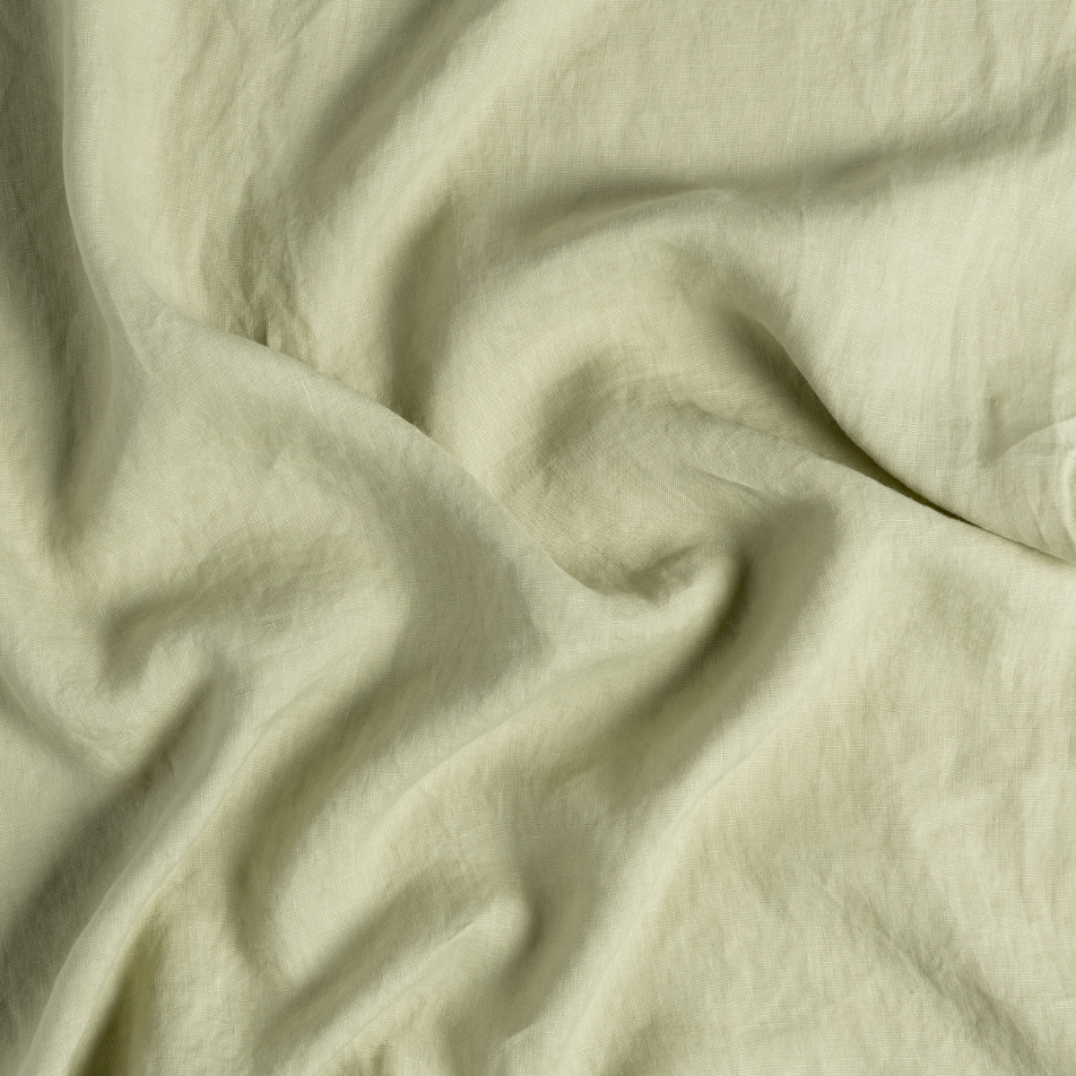Softly draped Desert Sage linen fitted sheet, showing natural wrinkled texture.