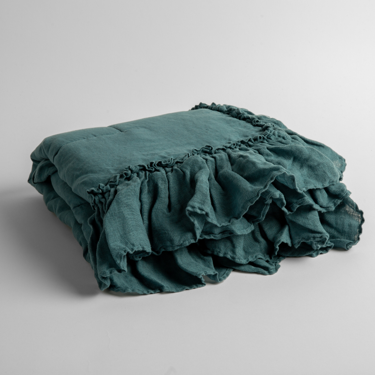 Folded Cenote linen baby blanket with cascading ruffle trim detail.
