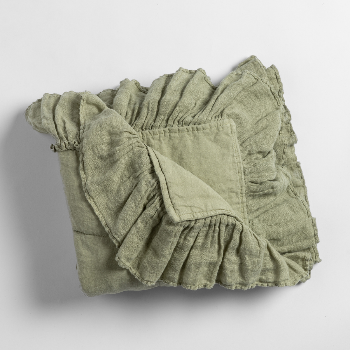 Folded Desert Sage linen baby blanket with gathered ruffle trim, shown on white background.