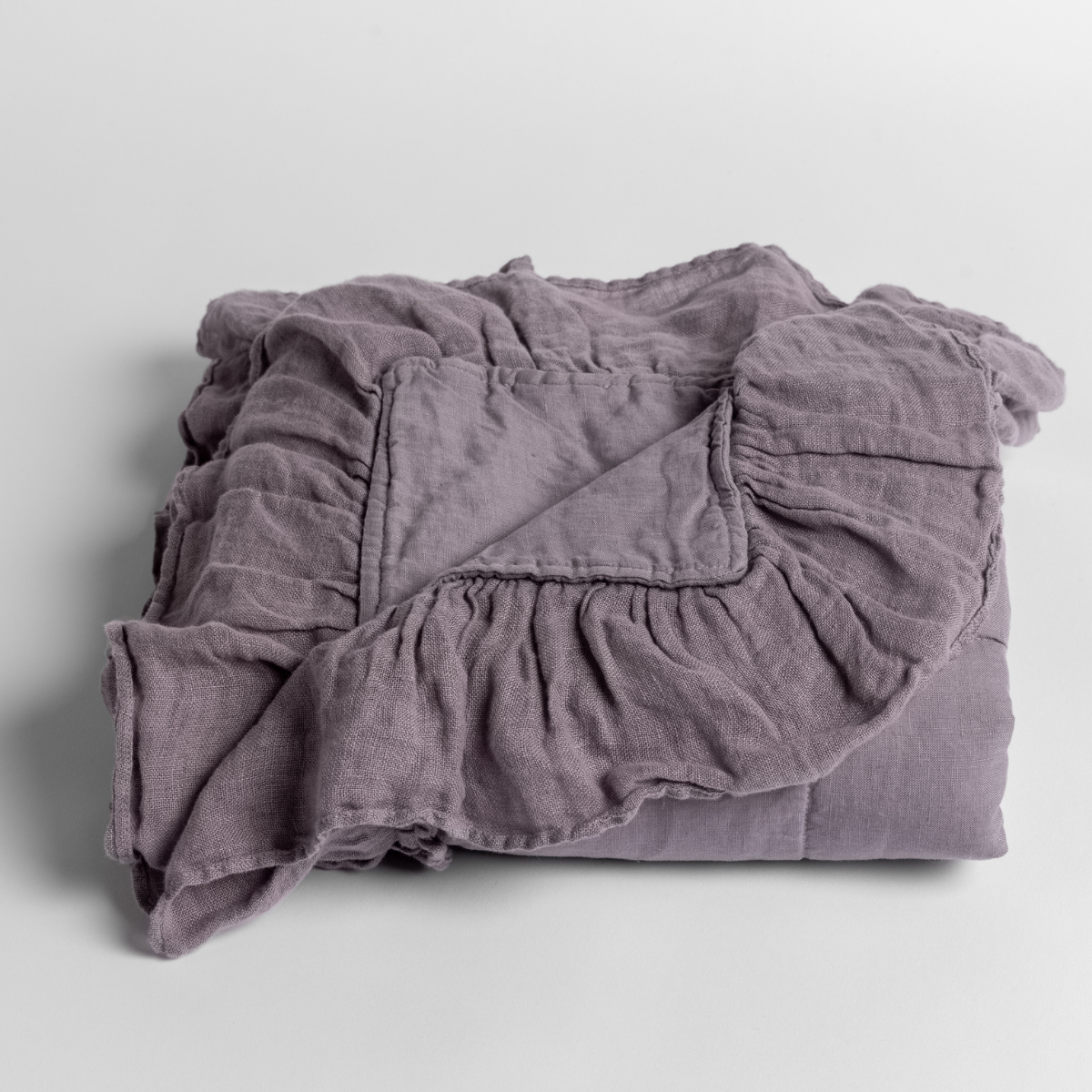 Folded French Lavender linen baby blanket with ruffled trim detail.