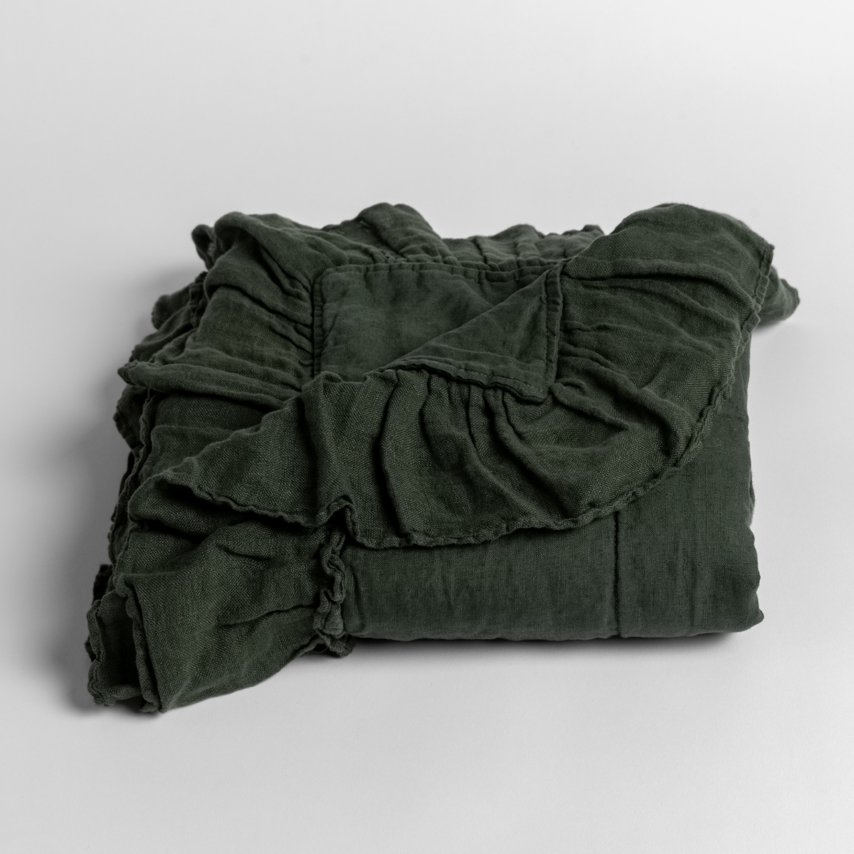 Folded Juniper linen baby blanket with ruffled trim detail, shown against neutral background.