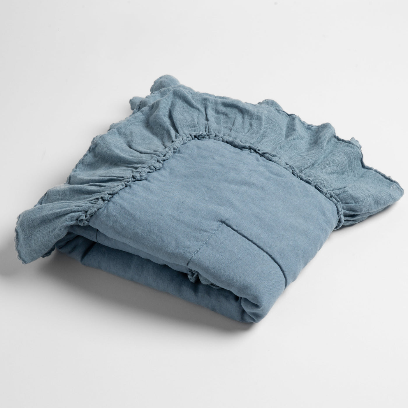 Folded Tahoe Blue linen fitted sheet showing elasticized corner detail against white background.
