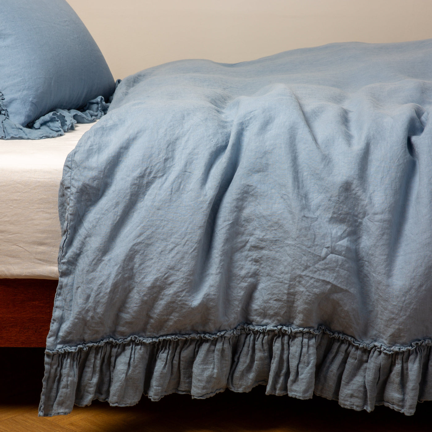 Ruffled hem detail on Bella Notte Linen Whisper duvet cover in Tahoe Blue, styled on bed.