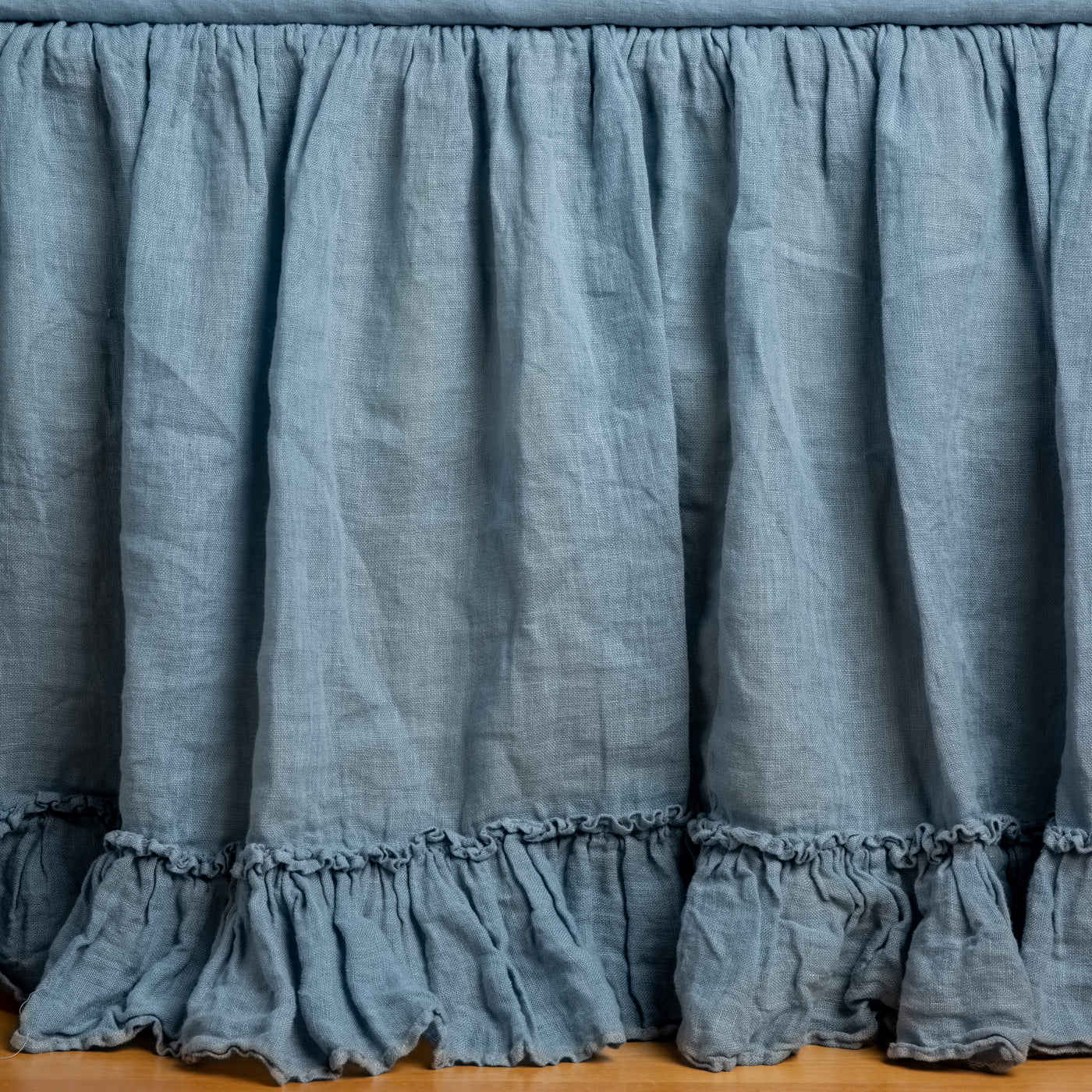 Gathered Tahoe Blue linen bed skirt with double ruffle hem, draped to floor.