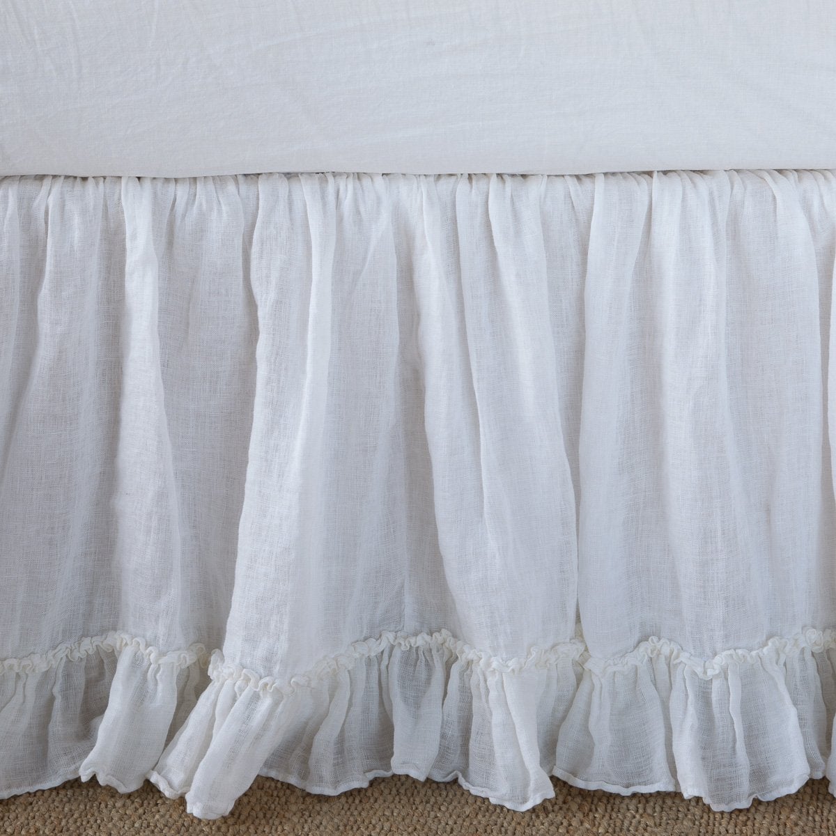 Bella Notte Linen Whisper bed skirt in White with ruffled hem, draped on bed frame.