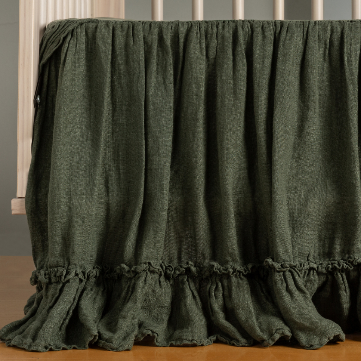 Bella Notte Linen Whisper crib skirt in Juniper, showing ruffled hem detail.